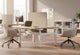 Aarhus Contour Task Chairs positioned at desks in a modern office interior, featuring two ergonomic chairs set against beige walls with wooden flooring, tall ceilings and large windows, highlighting contemporary task seating for professional workspaces.