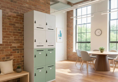 Moda Office Locker in a lounge and breakout area with exposed brick and white walls, wooden flooring, and tall windows. The locker features a powder-coated surface, ABS handles, and a front lock, positioned near chairs around a table, providing practical and stylish storage for modern office and collaborative spaces.